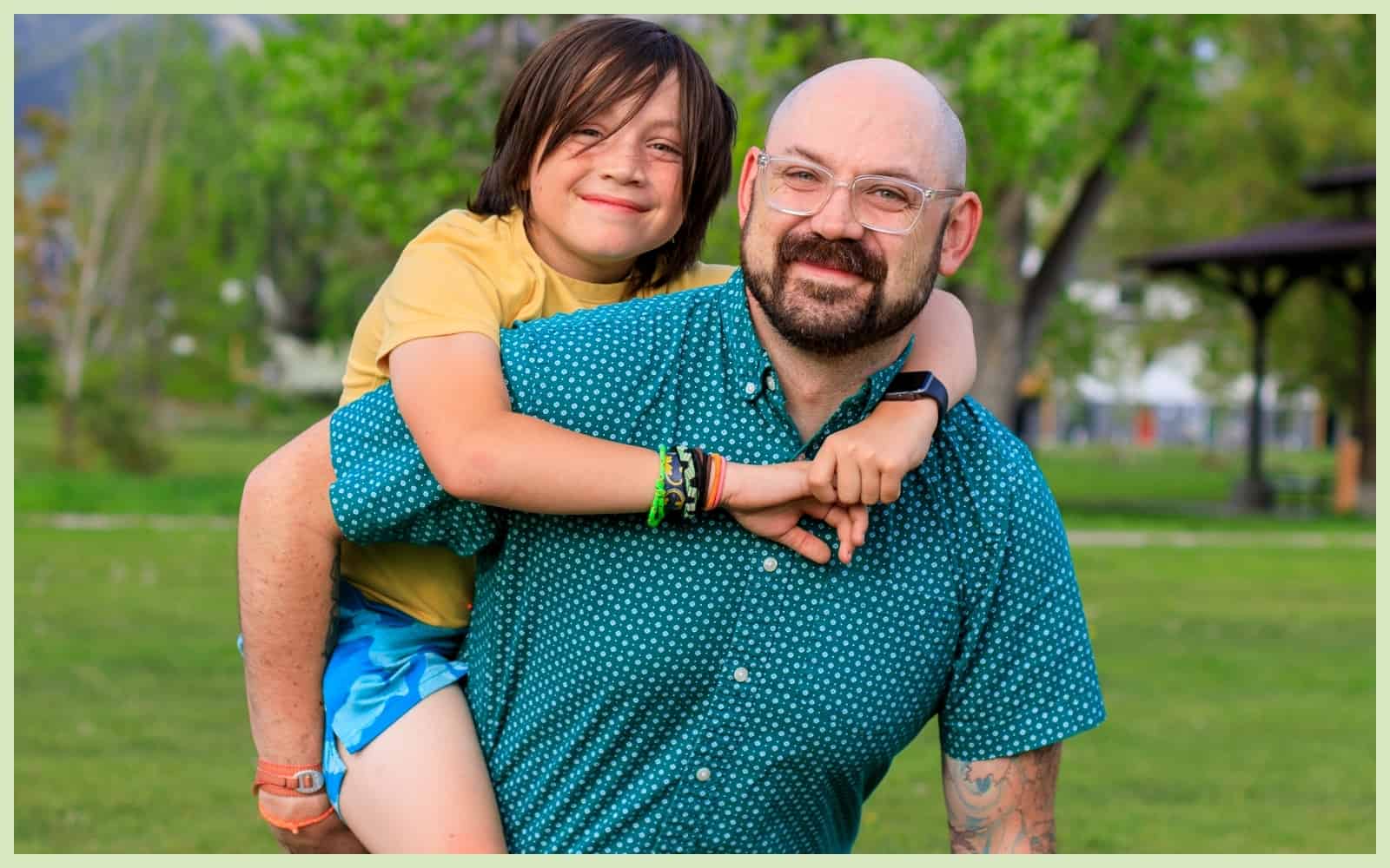 Patrick and his son pause a game of football at their local park to embrace and smile for a photo.