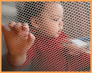Image of a happy baby, safely in a pack n play.